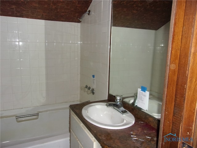 bathroom featuring large vanity and tiled shower / bath