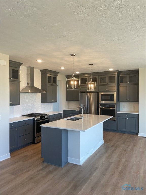 kitchen featuring appliances with stainless steel finishes, wall chimney exhaust hood, dark wood-type flooring, and an island with sink