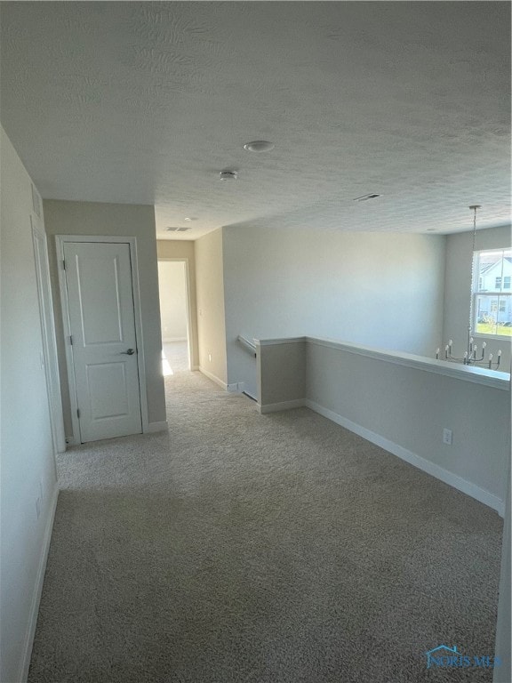 empty room with light carpet and a textured ceiling