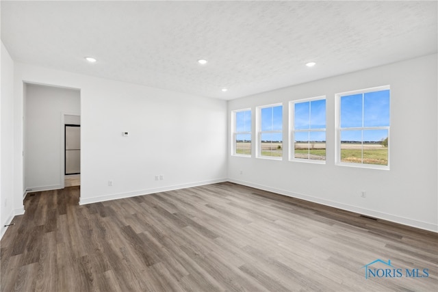 unfurnished room with a textured ceiling and hardwood / wood-style flooring