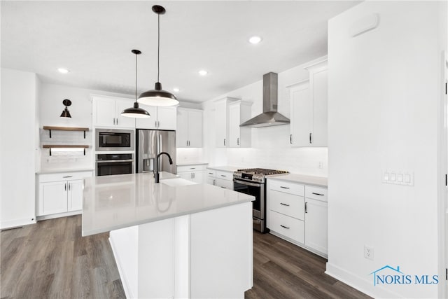 kitchen featuring hardwood / wood-style floors, wall chimney exhaust hood, sink, white cabinetry, and appliances with stainless steel finishes