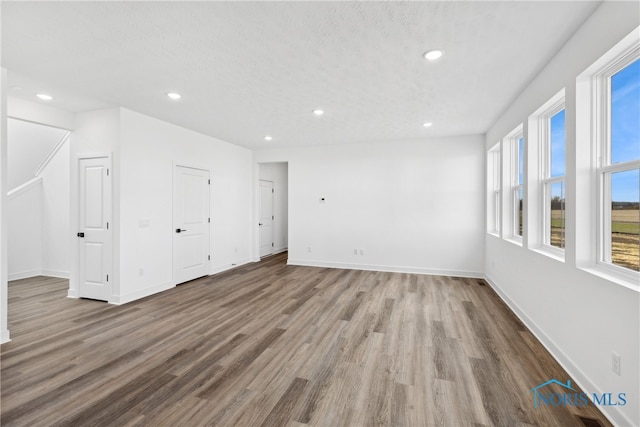 empty room featuring wood-type flooring, a healthy amount of sunlight, and a textured ceiling