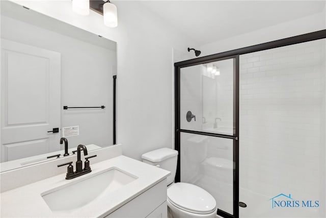 bathroom featuring vanity, toilet, and a shower with shower door