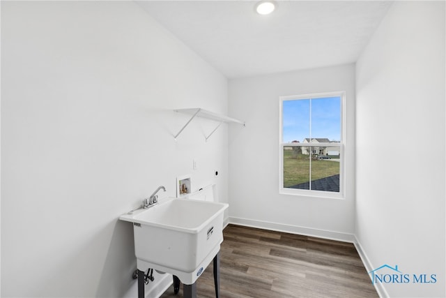 laundry room featuring electric dryer hookup, hookup for a washing machine, dark hardwood / wood-style floors, and sink