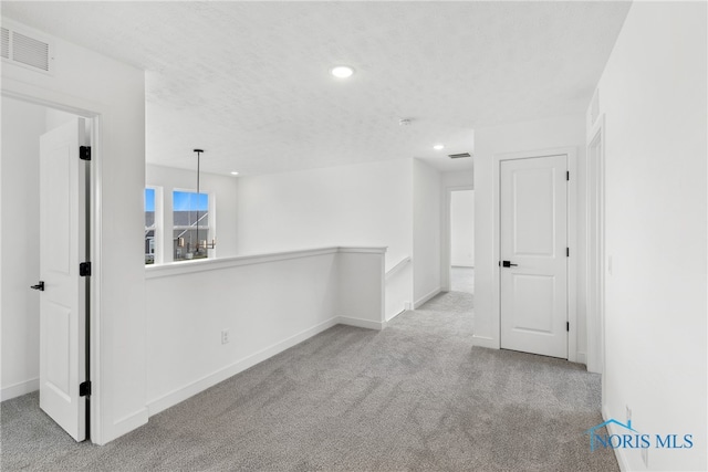 carpeted empty room with a textured ceiling