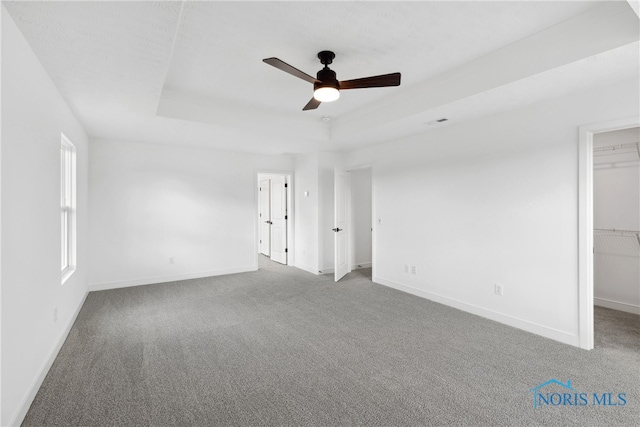 spare room featuring a tray ceiling, ceiling fan, and carpet floors