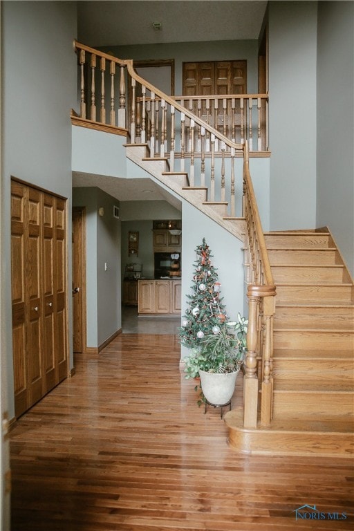 stairway featuring hardwood / wood-style flooring and a towering ceiling