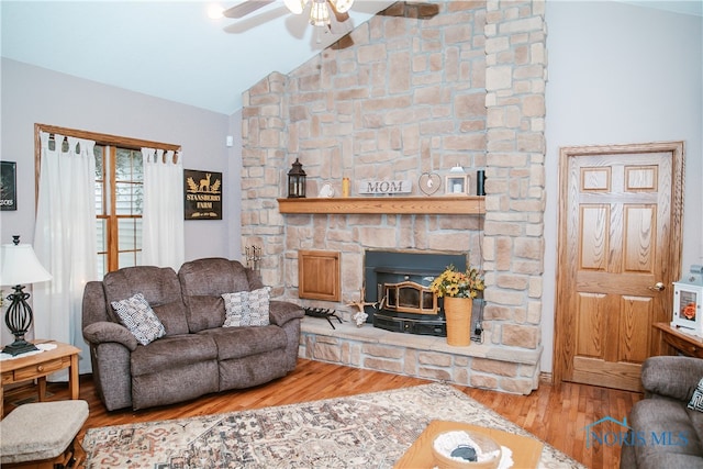 living room with lofted ceiling, a wood stove, ceiling fan, a fireplace, and wood-type flooring