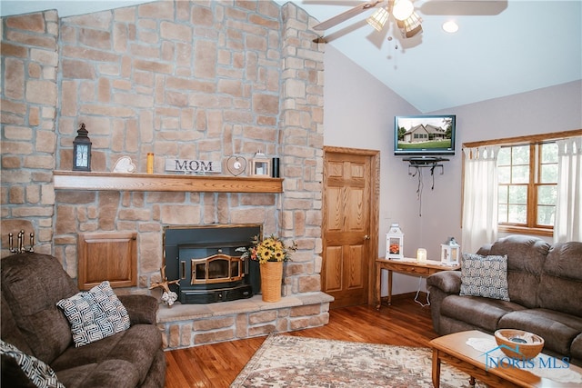 living room with a wood stove, ceiling fan, hardwood / wood-style floors, a fireplace, and vaulted ceiling