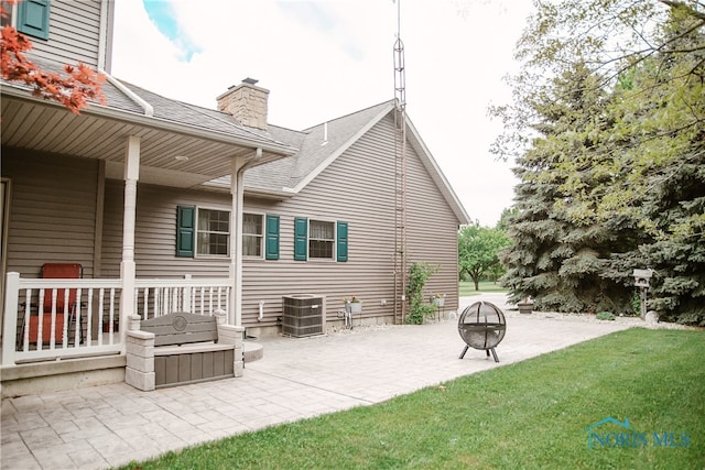 rear view of house featuring a patio, a yard, cooling unit, and a fire pit