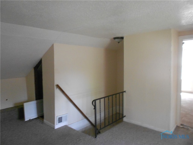 stairs with a textured ceiling, carpet floors, and lofted ceiling