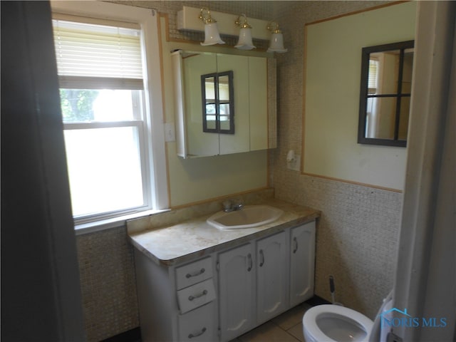 bathroom with plenty of natural light, tile flooring, toilet, and vanity