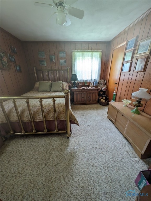 bedroom featuring carpet floors, ceiling fan, and wood walls