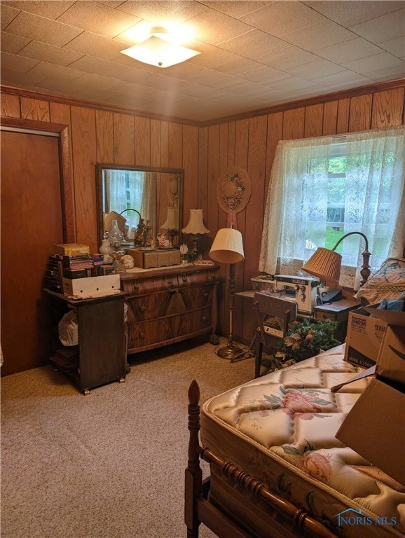 bedroom featuring light carpet and wooden walls