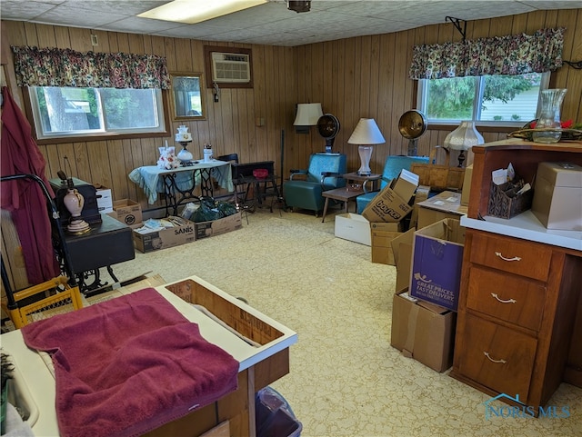 interior space with wooden walls, a wealth of natural light, and a paneled ceiling