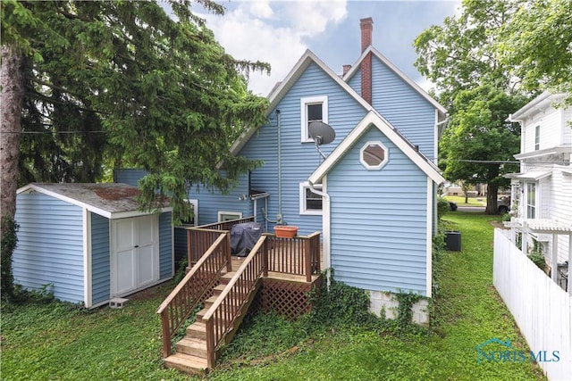 rear view of house with a storage unit, a yard, and a wooden deck