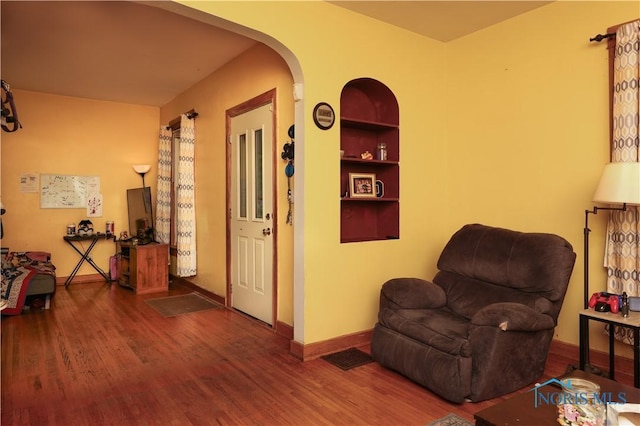 sitting room featuring hardwood / wood-style floors and built in shelves