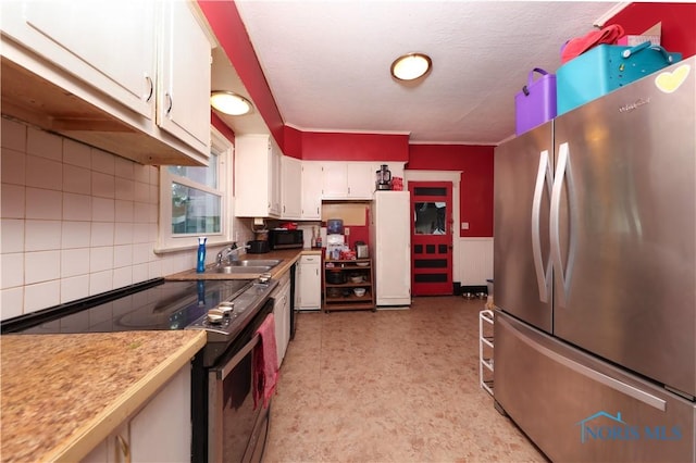 kitchen with appliances with stainless steel finishes, a textured ceiling, white cabinetry, and sink