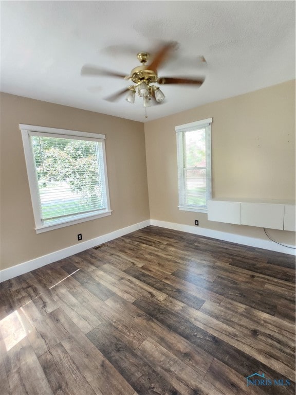 unfurnished room with dark hardwood / wood-style floors, plenty of natural light, and ceiling fan