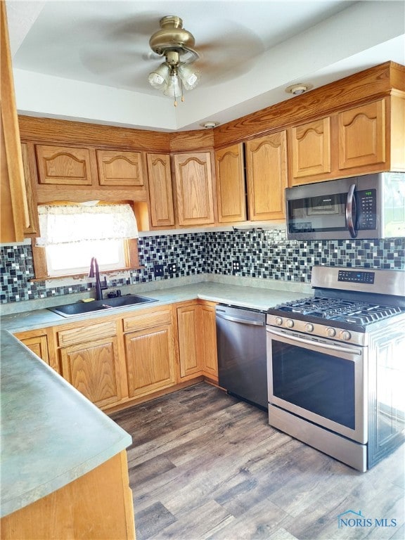 kitchen with dark hardwood / wood-style floors, ceiling fan, tasteful backsplash, appliances with stainless steel finishes, and sink