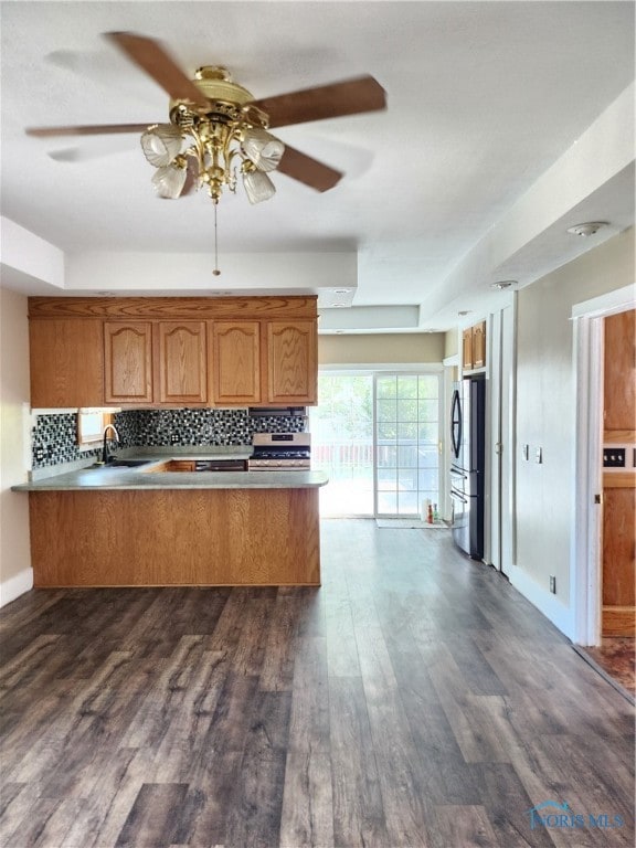 kitchen with a raised ceiling, ceiling fan, tasteful backsplash, and dark wood-type flooring