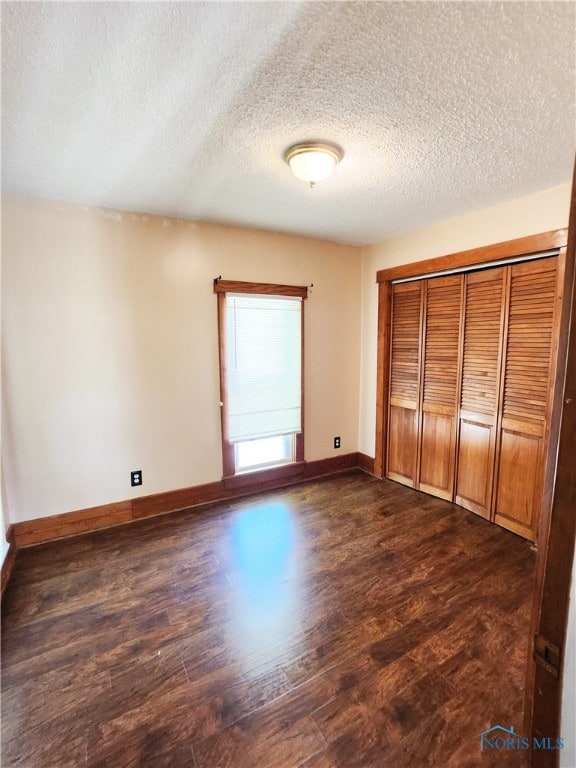 unfurnished bedroom with a textured ceiling, a closet, and dark hardwood / wood-style flooring