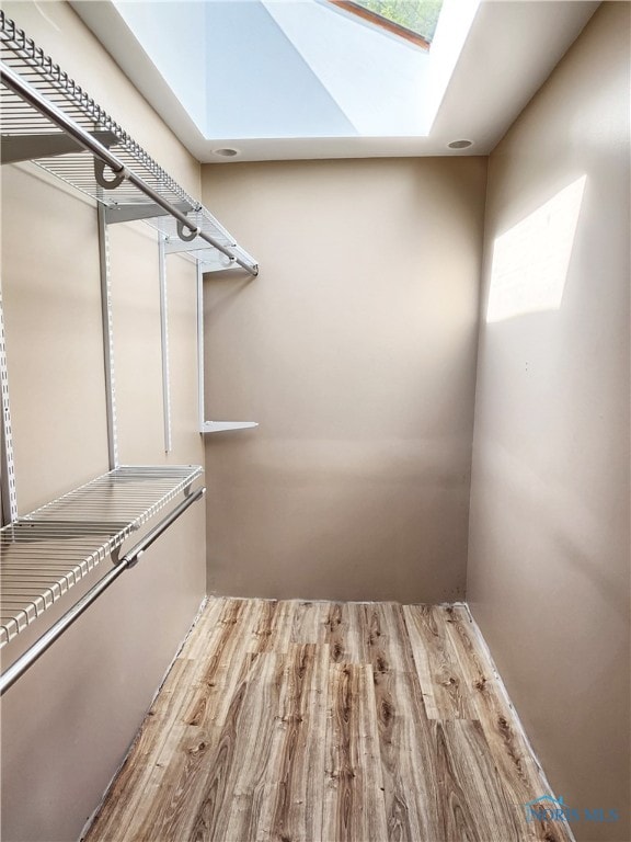 spacious closet featuring light hardwood / wood-style floors and a skylight