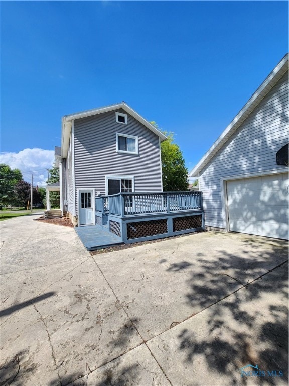 rear view of house with a wooden deck and a garage