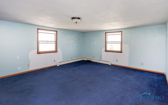 spare room with dark colored carpet, plenty of natural light, and baseboard heating