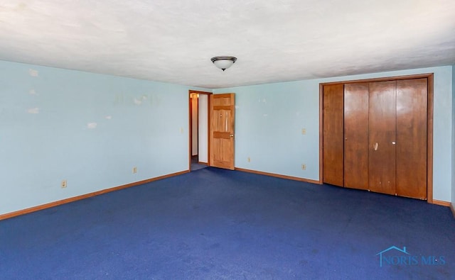 unfurnished bedroom with dark carpet and a closet