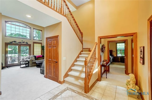 stairs featuring carpet floors, french doors, and a towering ceiling