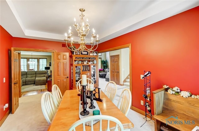 carpeted dining space featuring a raised ceiling and an inviting chandelier