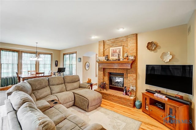 living room with a brick fireplace, hardwood / wood-style flooring, and an inviting chandelier