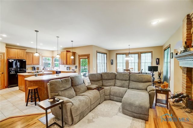 living room with a brick fireplace, light hardwood / wood-style floors, and a healthy amount of sunlight