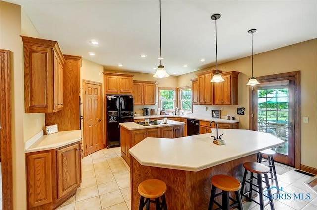 kitchen with black appliances, pendant lighting, a breakfast bar area, and a center island with sink