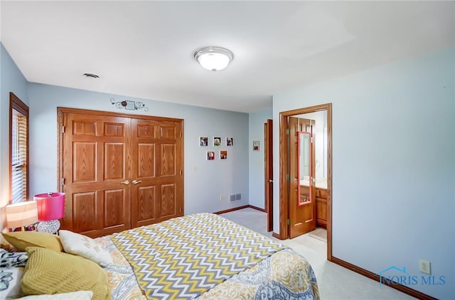 bedroom with light carpet, a closet, and ensuite bath