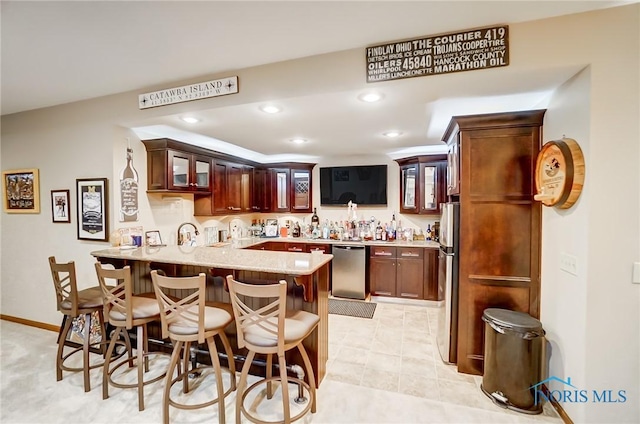 kitchen with a breakfast bar, kitchen peninsula, light tile patterned flooring, and stainless steel appliances