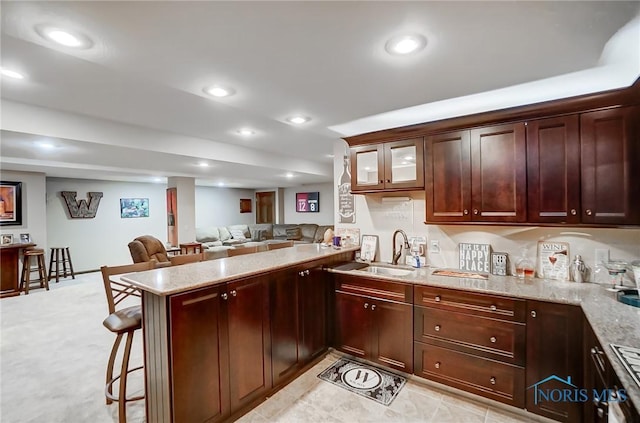 kitchen featuring light stone counters, sink, kitchen peninsula, and a breakfast bar