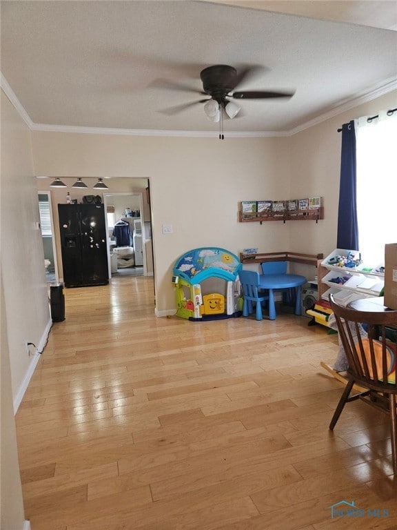 bedroom with wood-type flooring, black refrigerator, ceiling fan, and crown molding