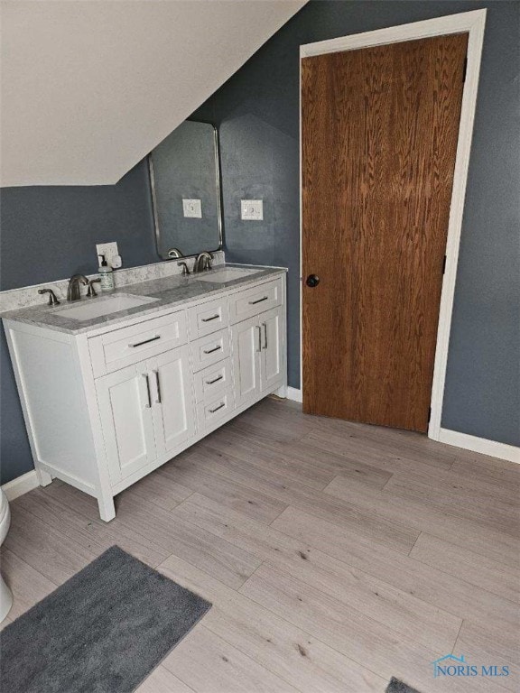 bathroom featuring hardwood / wood-style floors, vanity, toilet, and lofted ceiling