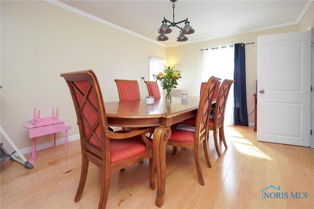 dining space with ornamental molding, light wood-type flooring, and an inviting chandelier