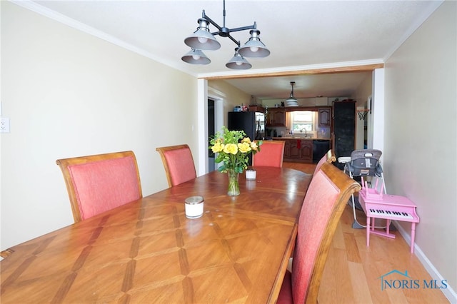 dining space featuring light hardwood / wood-style floors, crown molding, and an inviting chandelier