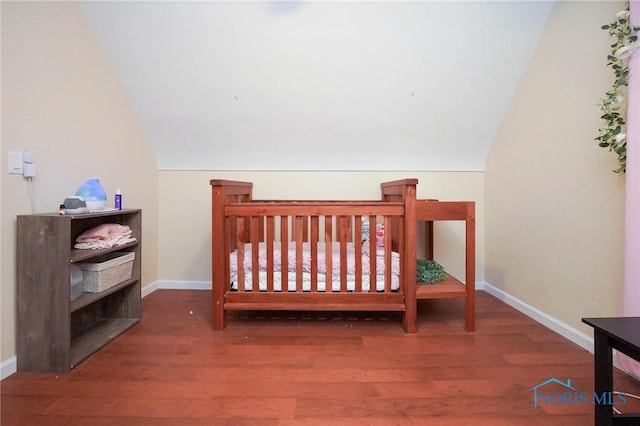 bedroom featuring a nursery area, wood-type flooring, and lofted ceiling