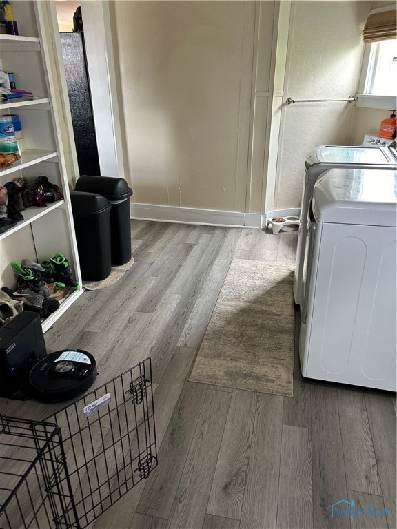 clothes washing area with washing machine and dryer and light wood-type flooring