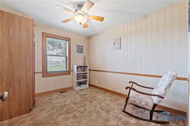 living area featuring light carpet and ceiling fan