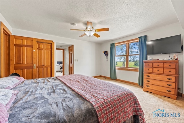 bedroom with ceiling fan, light colored carpet, and a textured ceiling