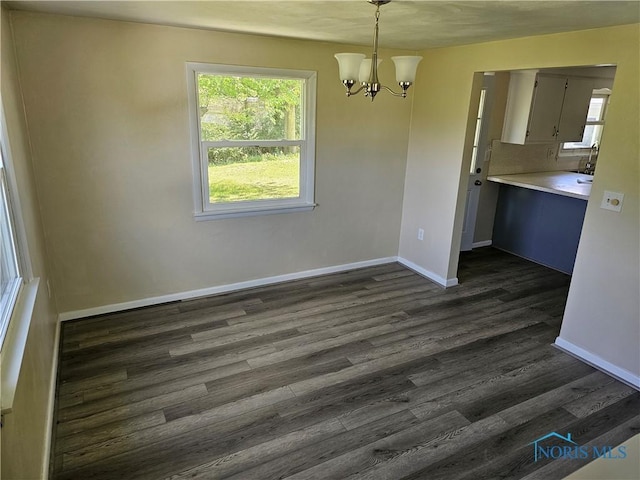 unfurnished dining area with dark wood-type flooring and a notable chandelier