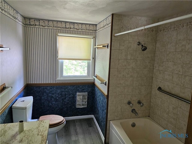 bathroom with hardwood / wood-style floors, toilet, and tiled shower / bath