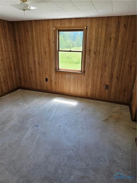 empty room with concrete floors and wooden walls