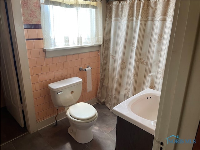 bathroom featuring tile floors, vanity, toilet, and tile walls